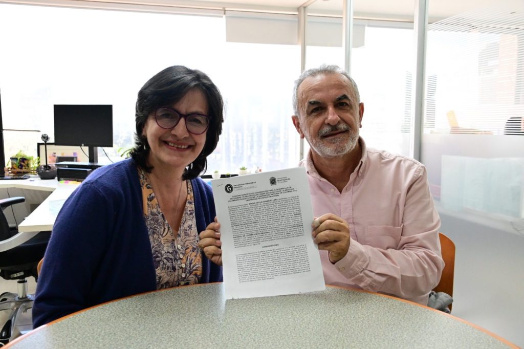Fotografía de la Vicerrectora de gestión Universitaria y German Alfonso Palacio Castañeda mostrando el convenio firmado.
