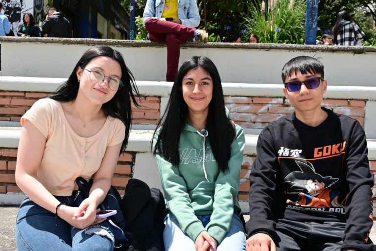 Tres estudiantes sentados en las gradas del bloque C